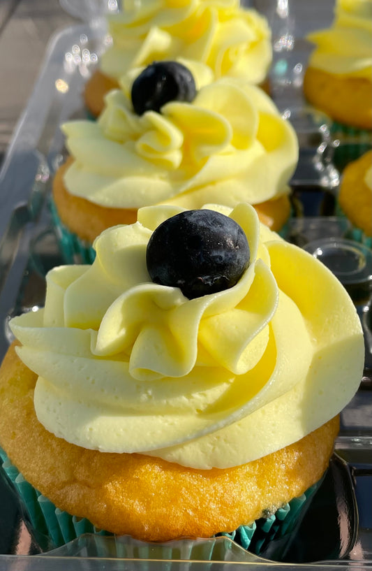 Lemon-Blueberry-A light and deliciously moist lemon cake with blueberries and lemon buttercream icing, topped with a blueberry. Speciality option - filled with lemon pudding or icing.